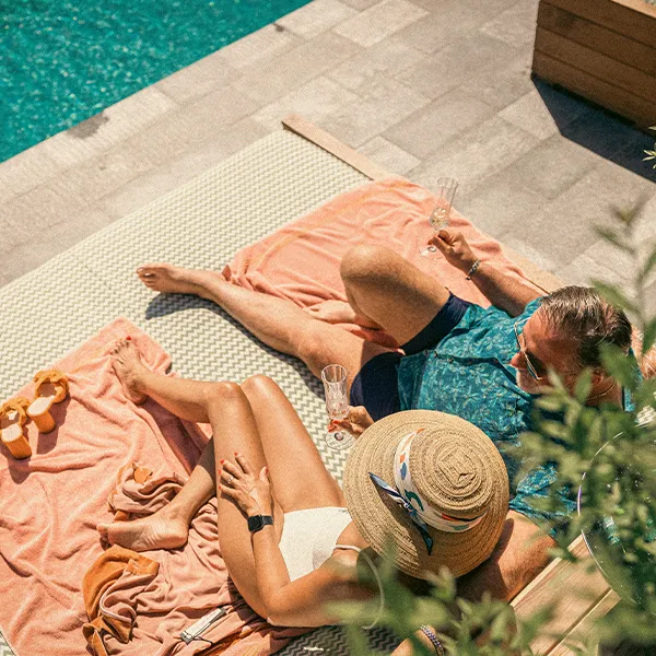 Avkoppling vid poolen på Hjortviken Par som solar och kopplar av vid poolen på Hjortviken med dryck i handen under en spaweekend.